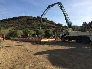A concrete pump is being used to pump concrete into a dirt field.