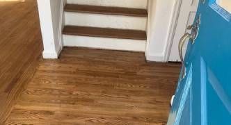 A blue door is open to a hallway with wooden floors and stairs