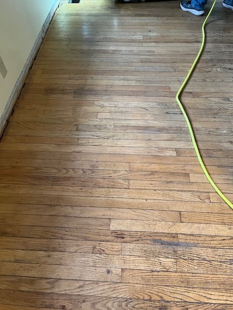 A person is standing on a wooden floor next to a yellow cord