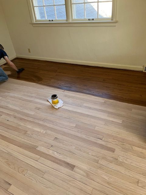 A person is painting a wooden floor in a room