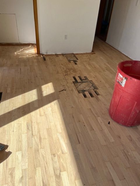 A red trash can is sitting on a wooden floor in a room