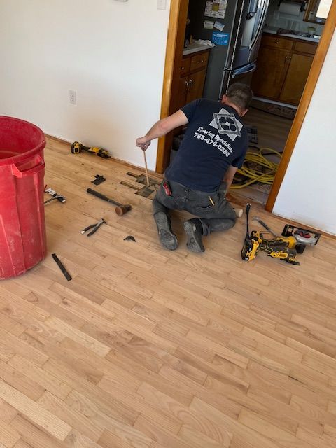 A man is kneeling down on a wooden floor with tools
