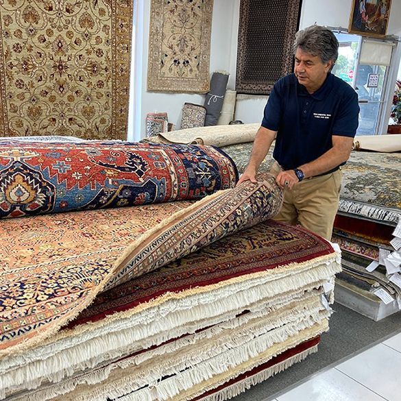 A man is standing next to a pile of rugs in a store.