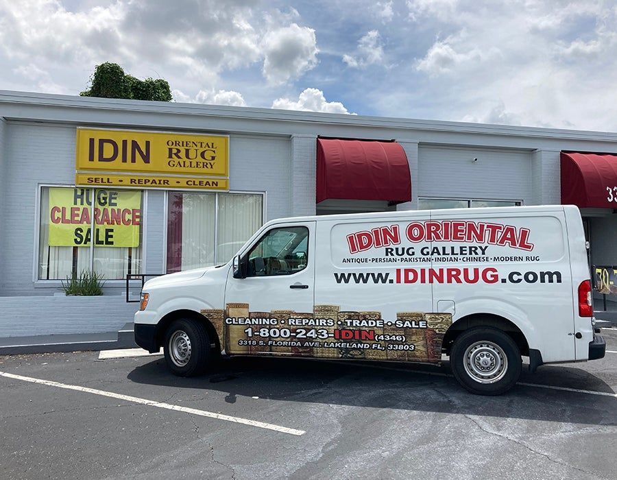 A white van is parked in front of an idn oriental rug gallery