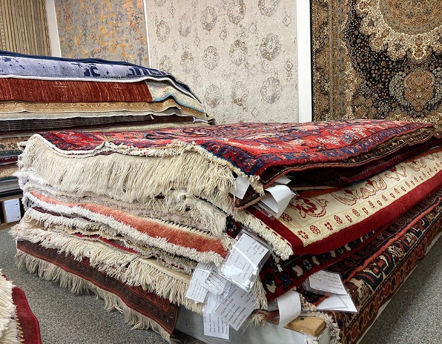 A bunch of rugs are stacked on top of each other in a room.