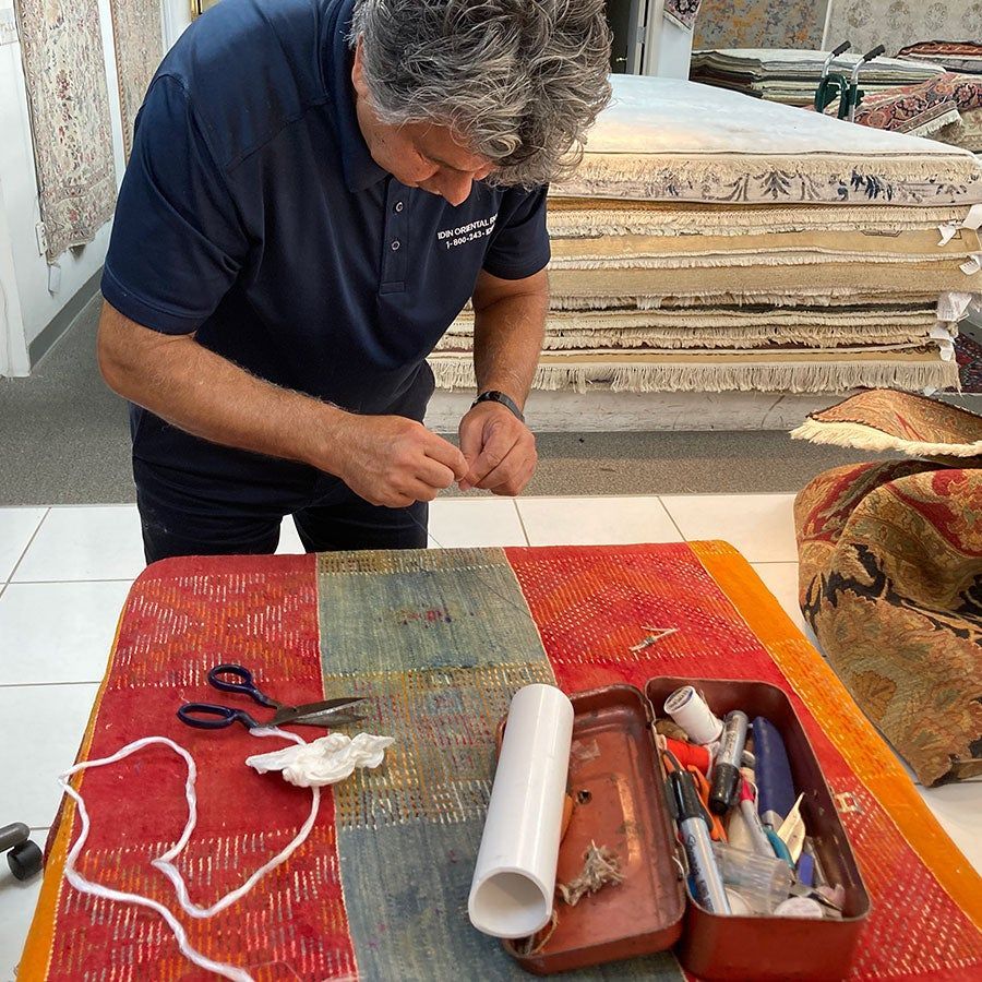 A man in a blue shirt is working on a rug
