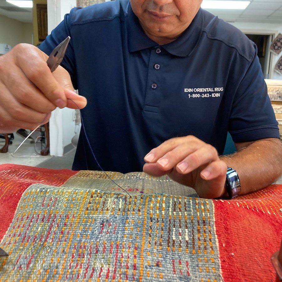 A man in a blue shirt is working on a piece of fabric