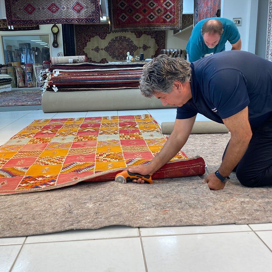 Two men are working on a rug in a store