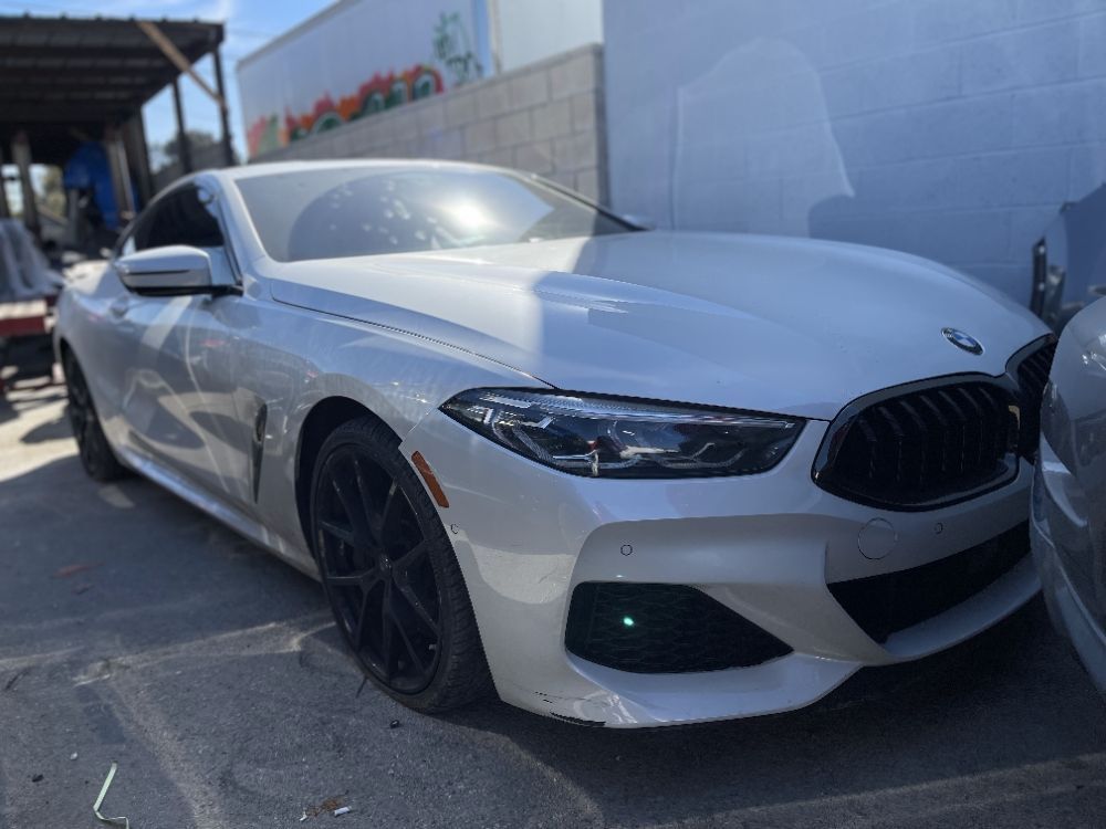 Silver BMW sedan parked outdoors in bright sunlight, front-left view.
