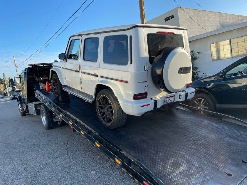 White SUV on a flatbed tow truck on a city street