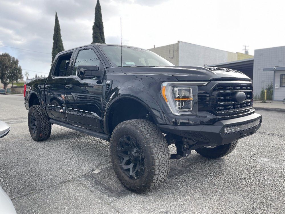 Black lifted pickup truck parked in a lot, side view under cloudy sky
