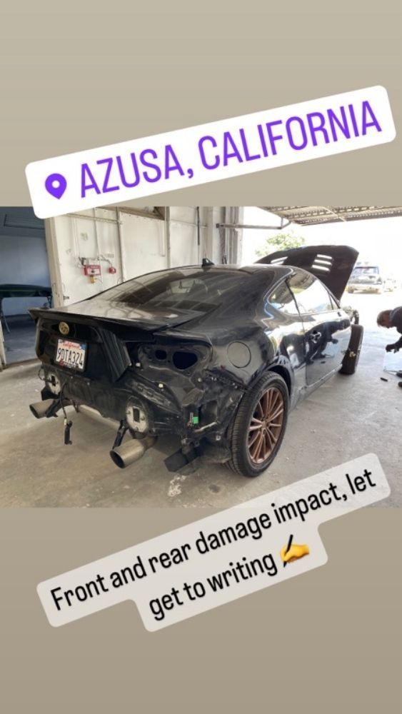 Black sports car with severe front and rear damage in a garage, tagged “Azusa, California”