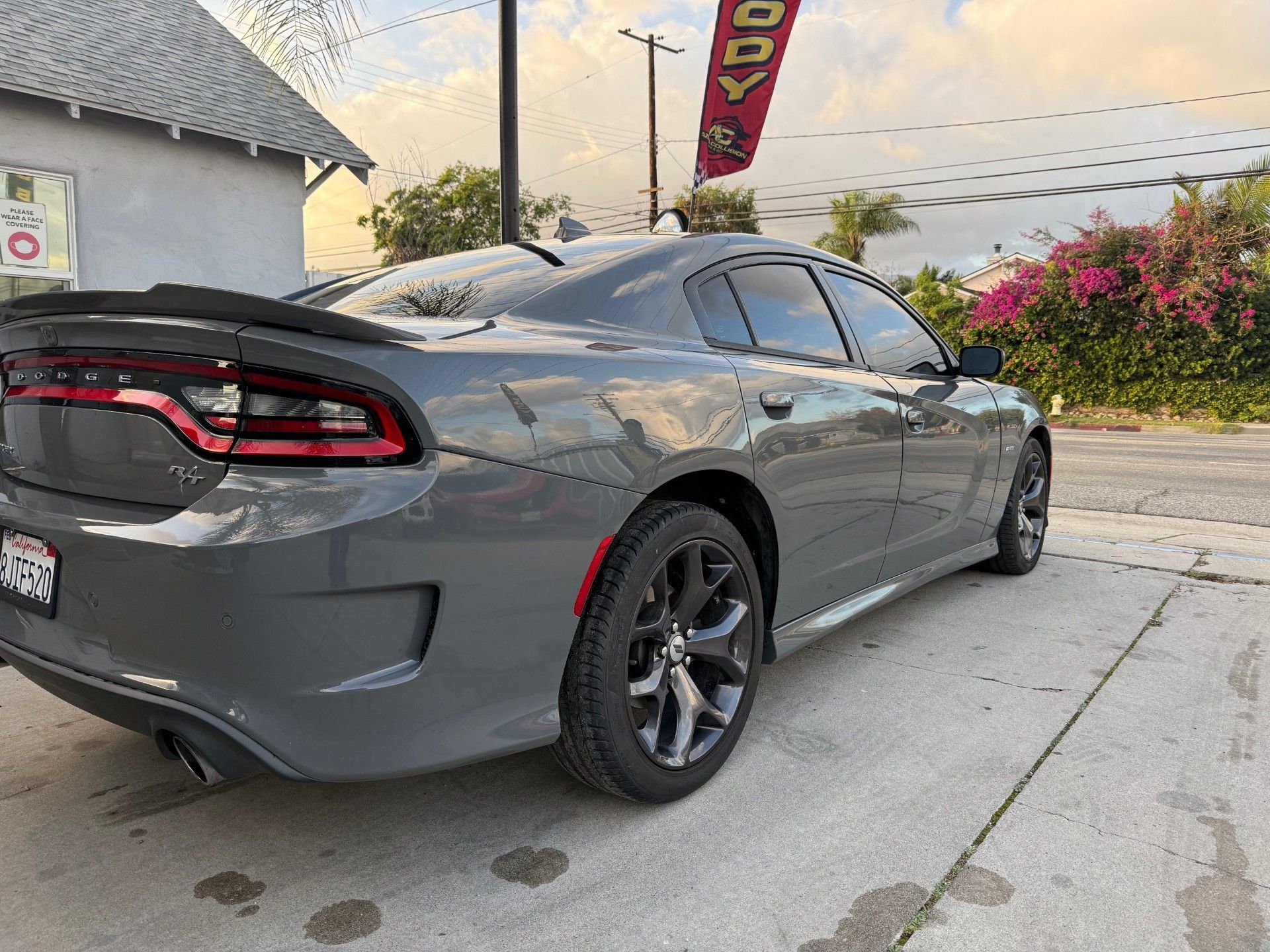 Gray sports coupe parked in a driveway beside a house, rear three-quarter view