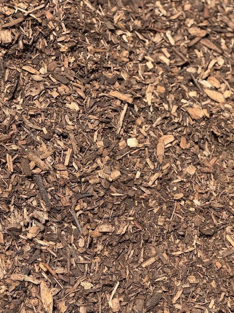 A pile of brown mulch is sitting on the ground.