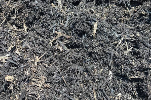 A pile of black mulch is sitting on the ground.