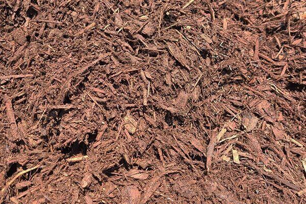 A pile of brown mulch is sitting on the ground.