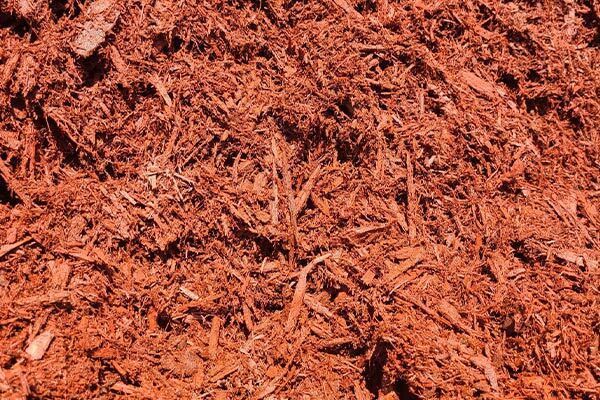 A pile of red mulch is sitting on the ground.