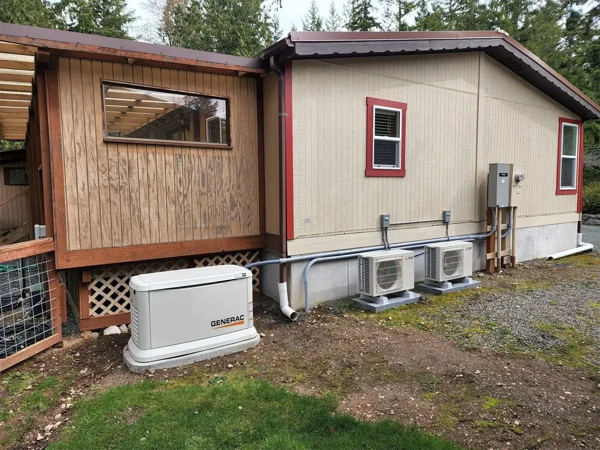 Generator and HVAC units next to a light-colored building with a brown roof and a wooden extension.