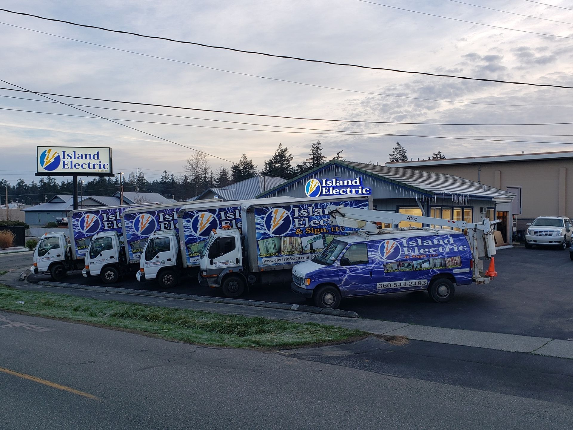 Several Island Breeze service trucks parked in front of a building with Island Breeze signage. Cloudy sky.