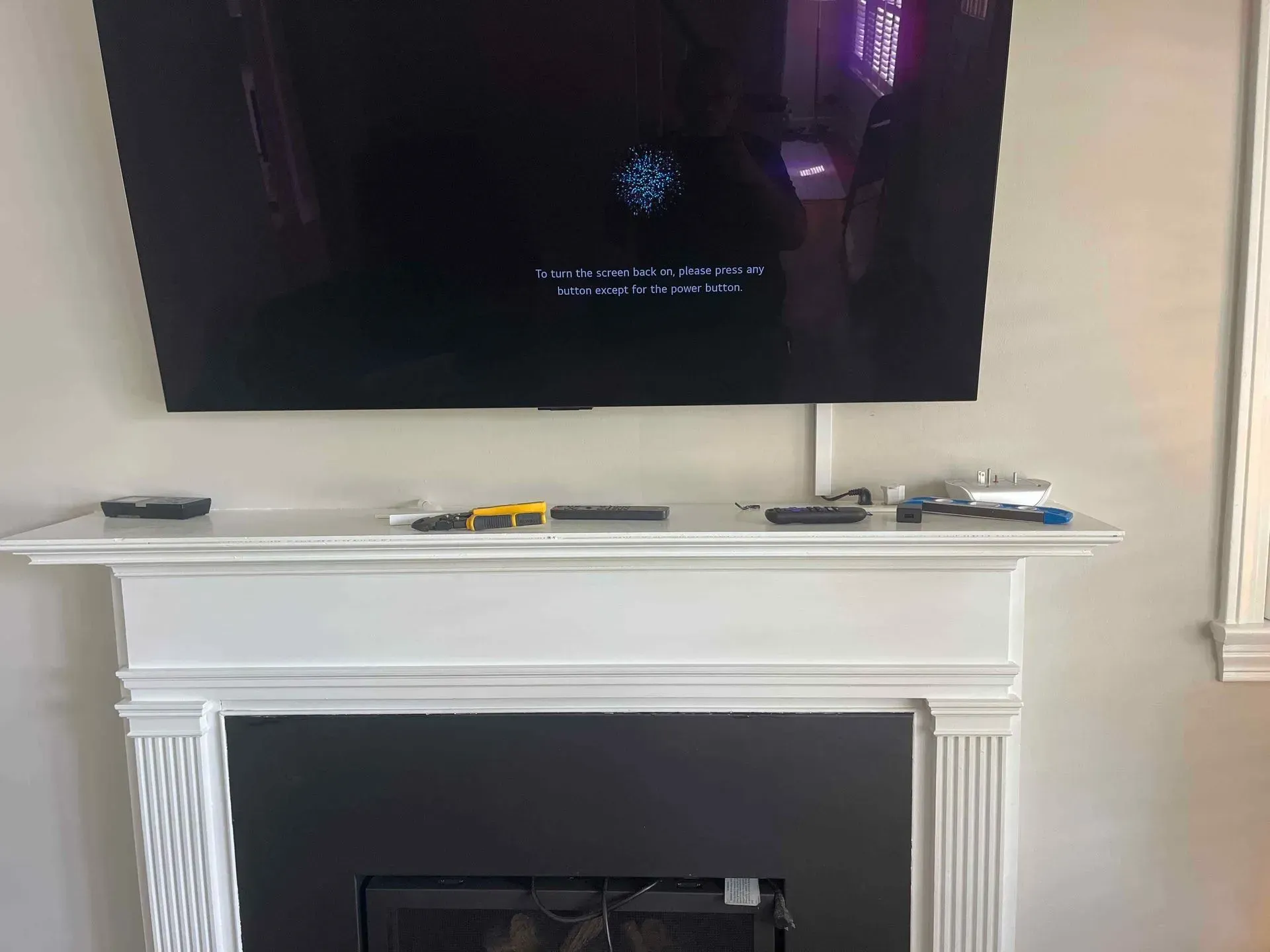 A flat-screen television mounted above a white fireplace mantel, with a loading screen visible on the display.