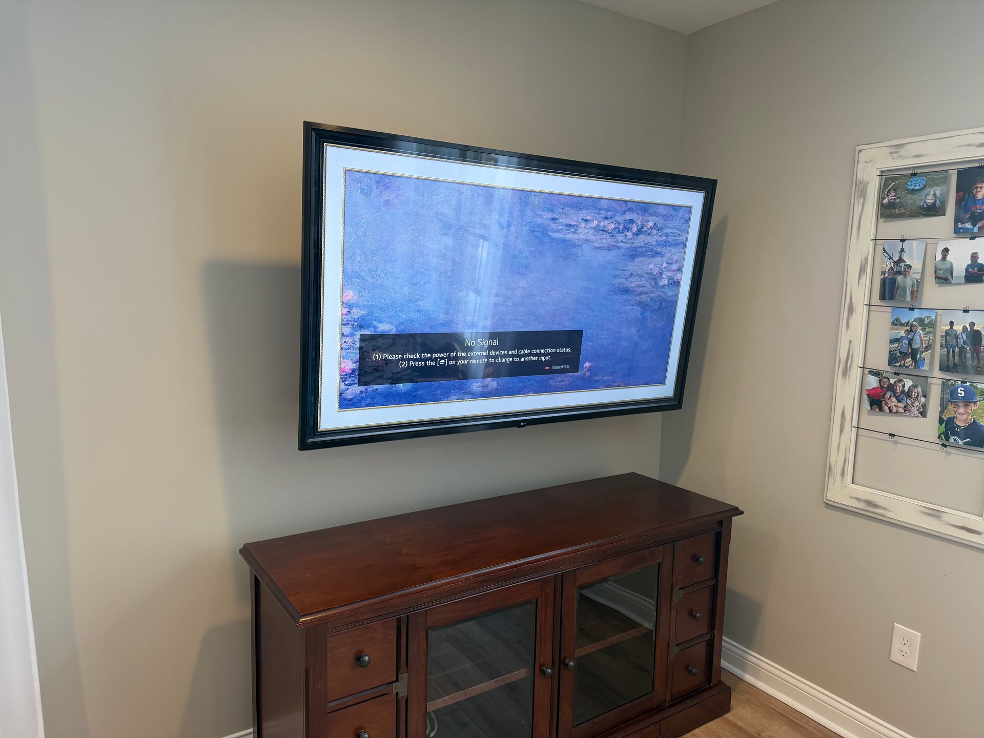 A wall-mounted flat-screen TV displaying a video game menu, positioned above a wooden media console in a room.