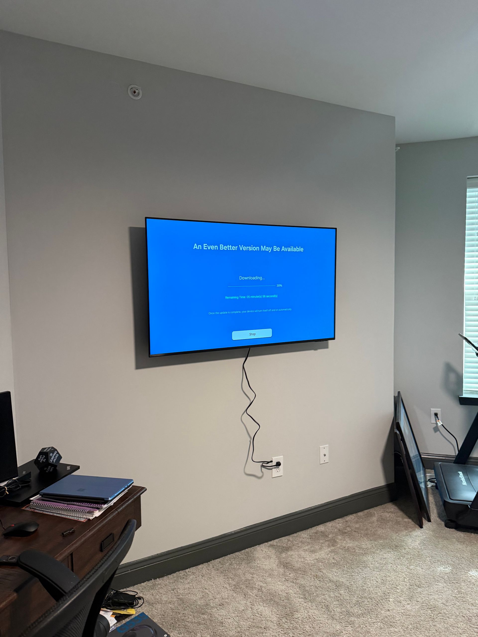 A wall-mounted TV displays a blue Windows error screen in a room with a desk and treadmill.