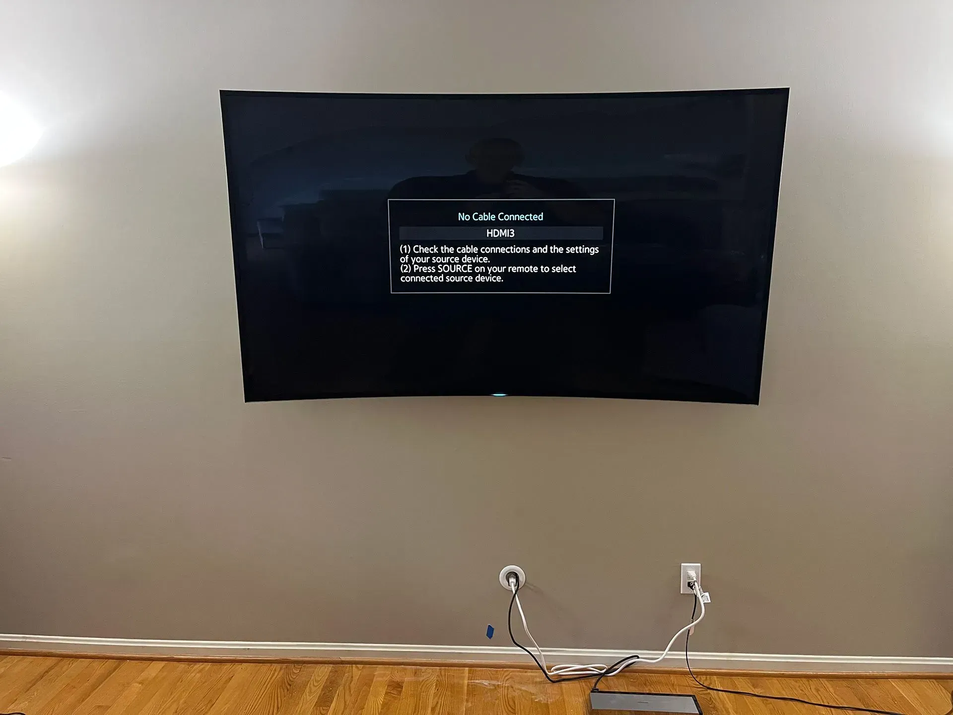 A large flat-screen TV mounted on a light gray wall displays a 