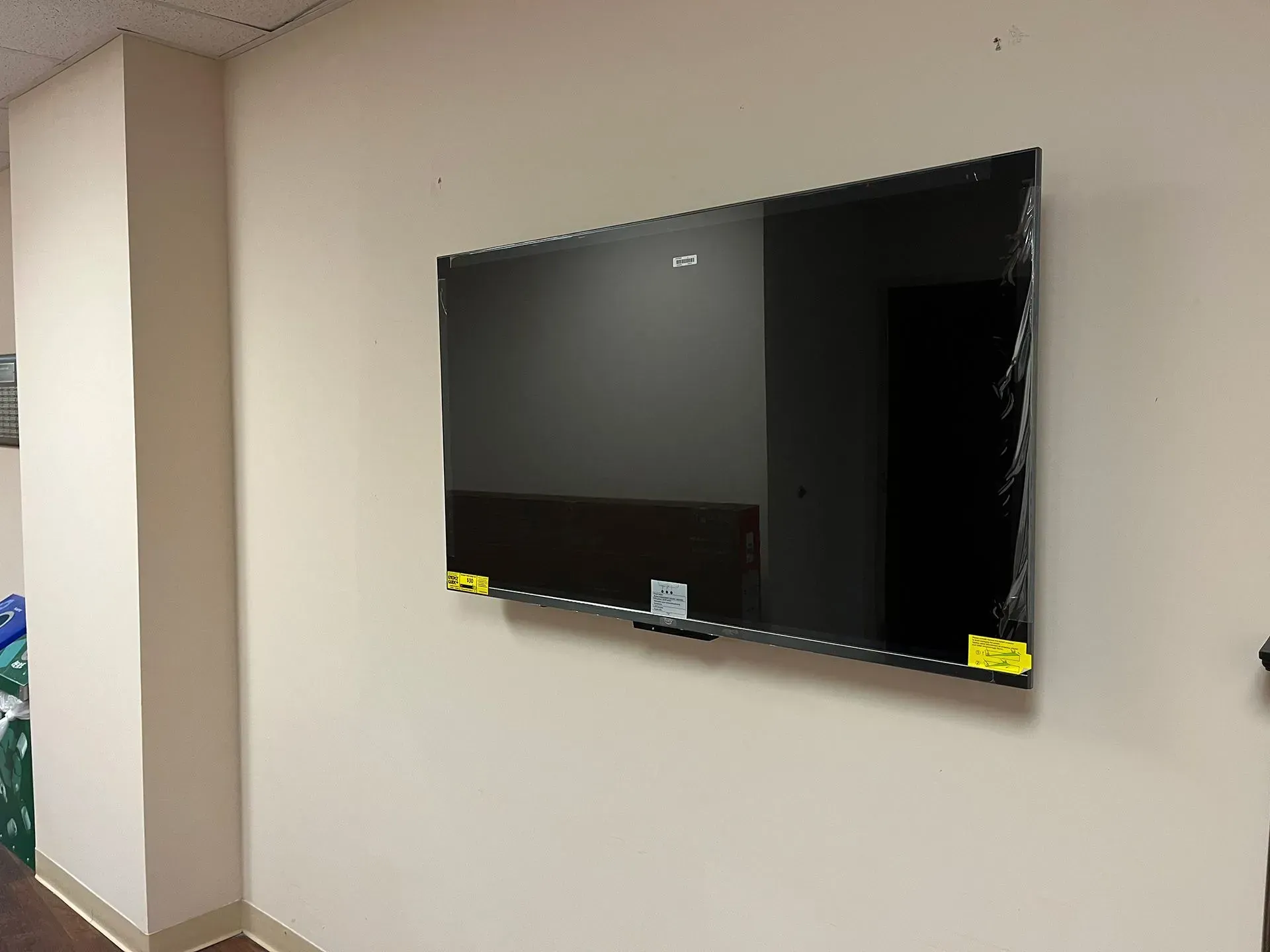 A flat-screen television mounted on a plain, light-colored wall in an indoor setting.