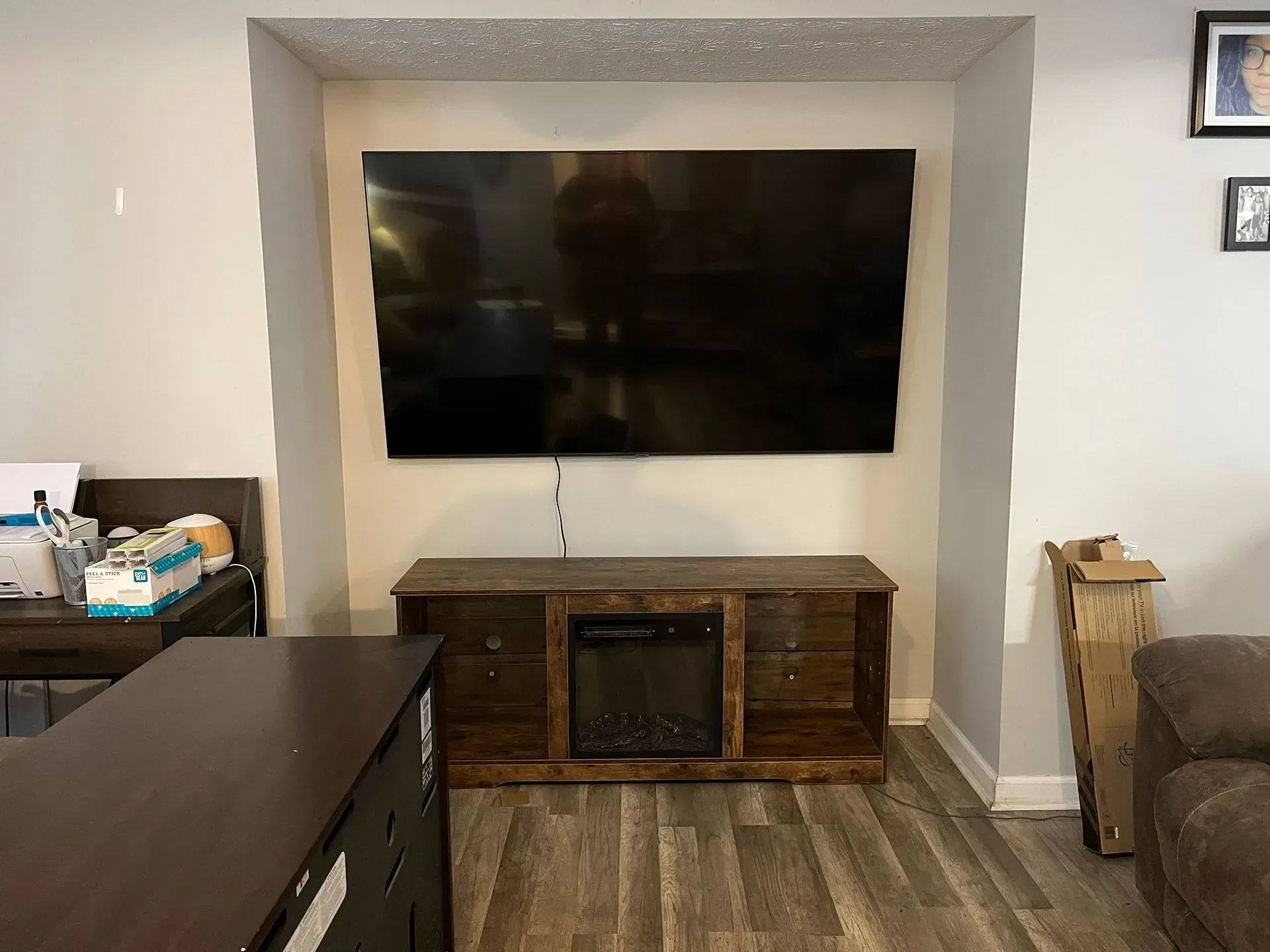 A large wall-mounted television sits above a dark wood media console with a built-in electric fireplace in an alcove.