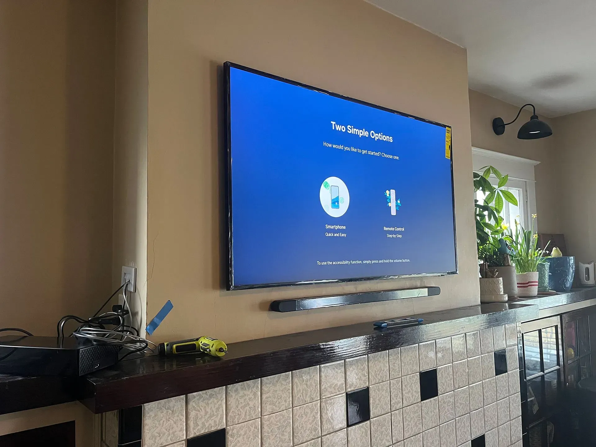 A large wall-mounted flat-screen TV displaying a setup screen above a soundbar on a tiled fireplace mantel.