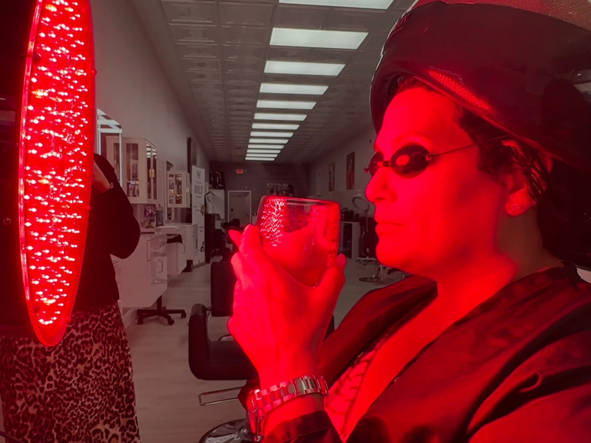A woman is holding a glass in front of a red light