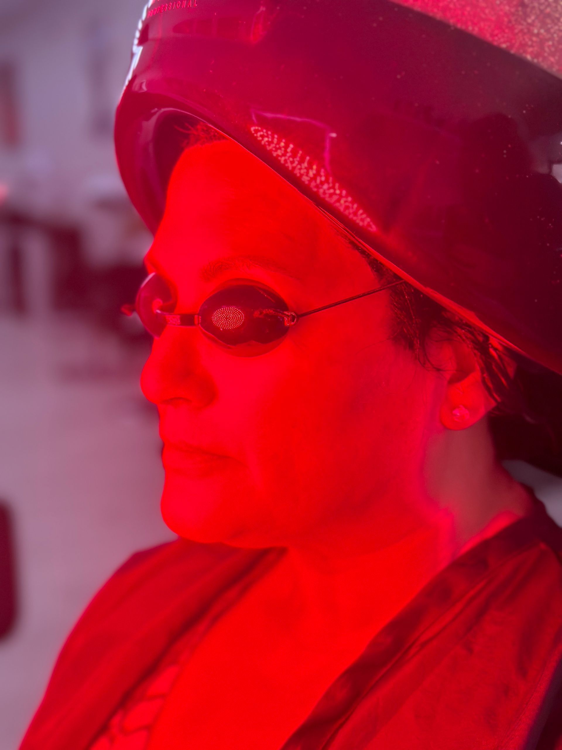 A woman wearing a hat and sunglasses is lit up in red light