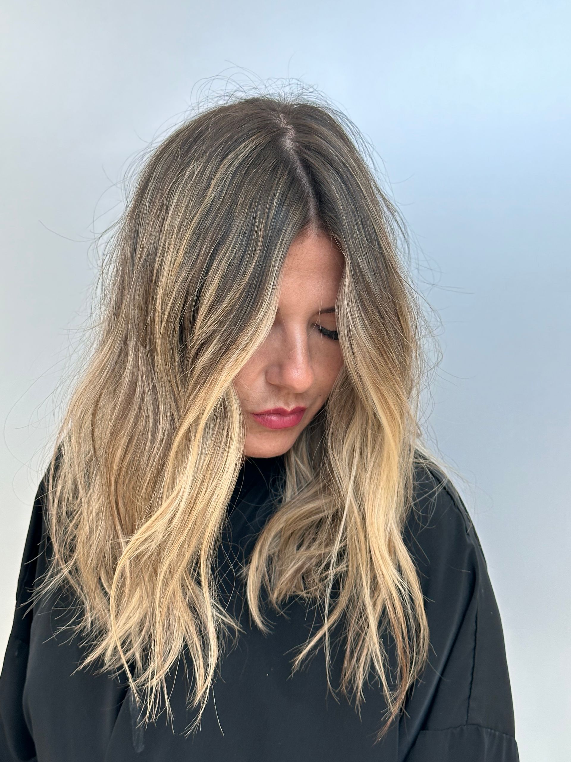 A woman with long blonde hair is wearing a black sweater.