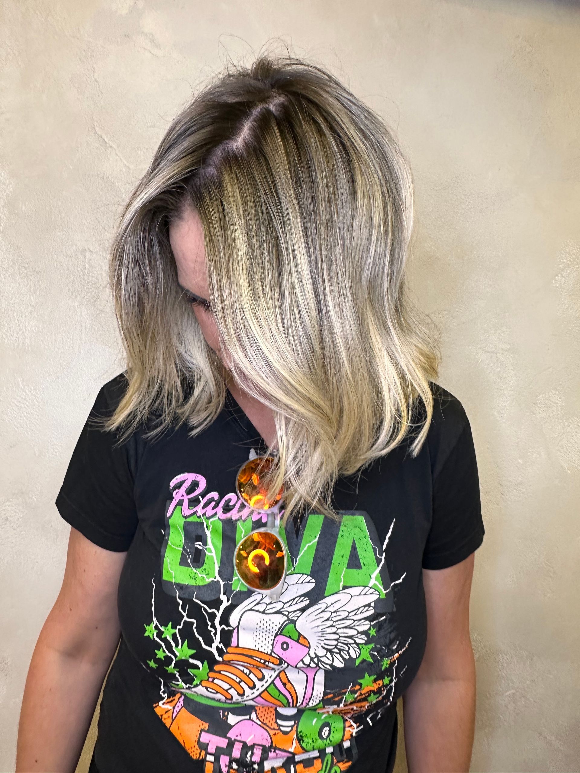 A woman with blonde hair is wearing a black t-shirt with a pegasus on it.