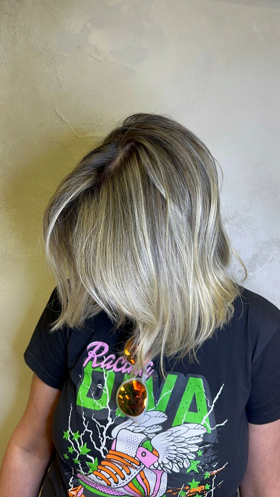 A woman with blonde hair is wearing a black t-shirt.