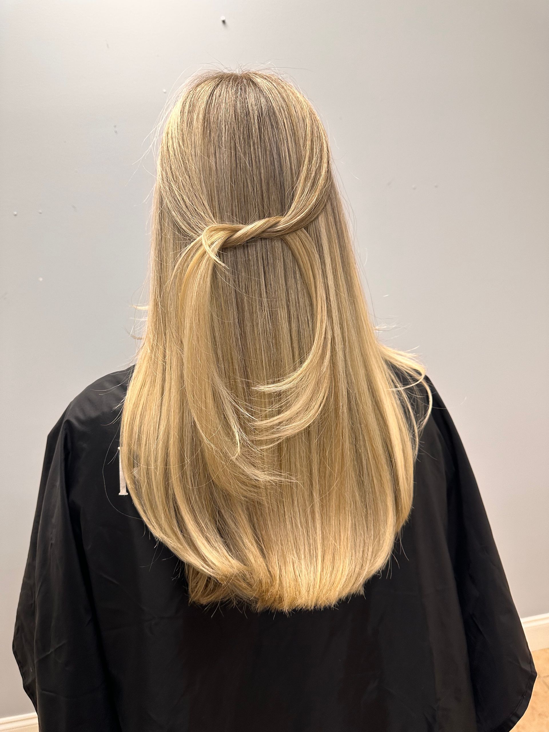 A woman with long blonde hair is wearing a black cape.