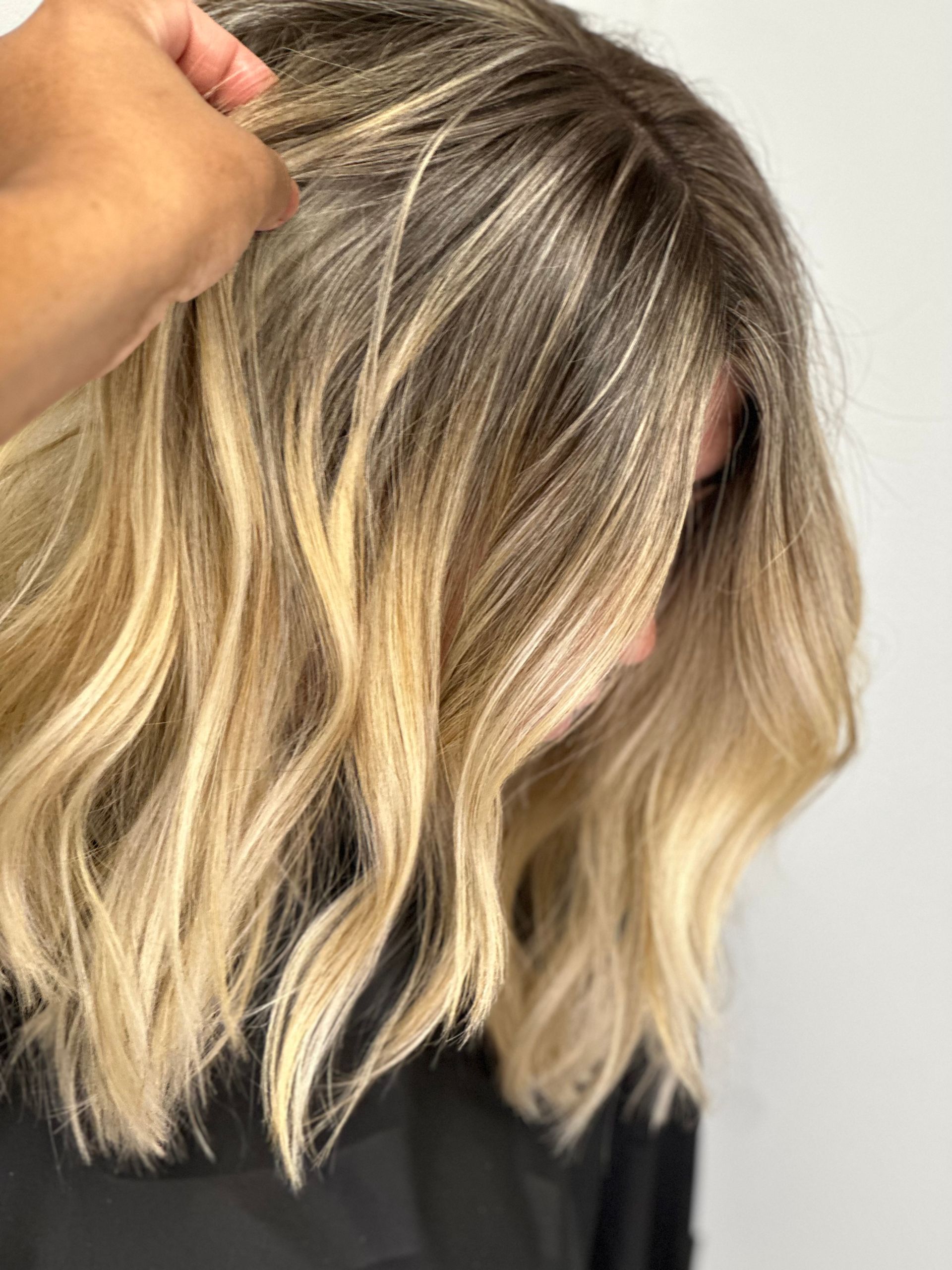 A woman with blonde hair is getting her hair cut by a hairdresser.