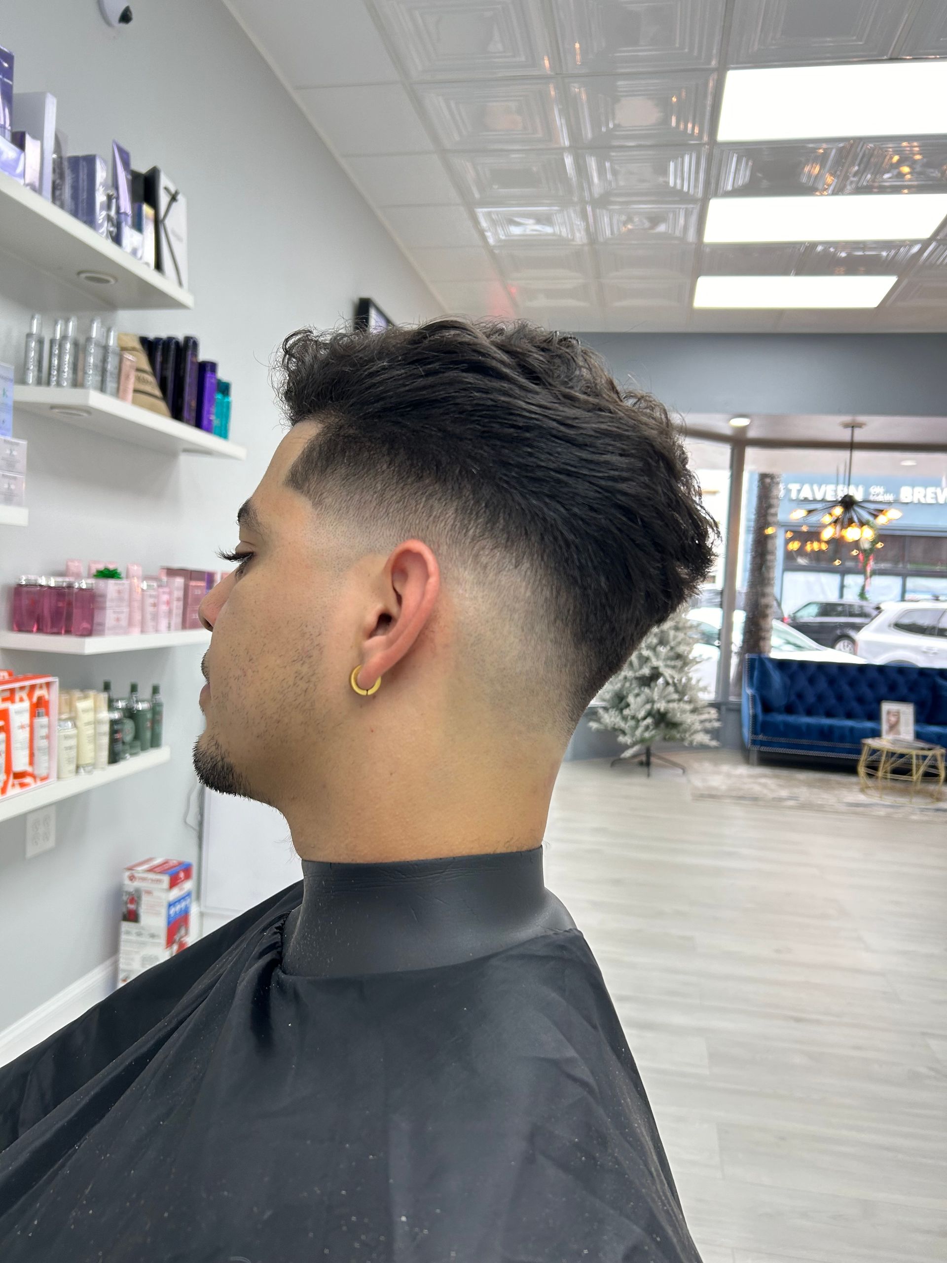 A man is getting his hair cut at a barber shop.