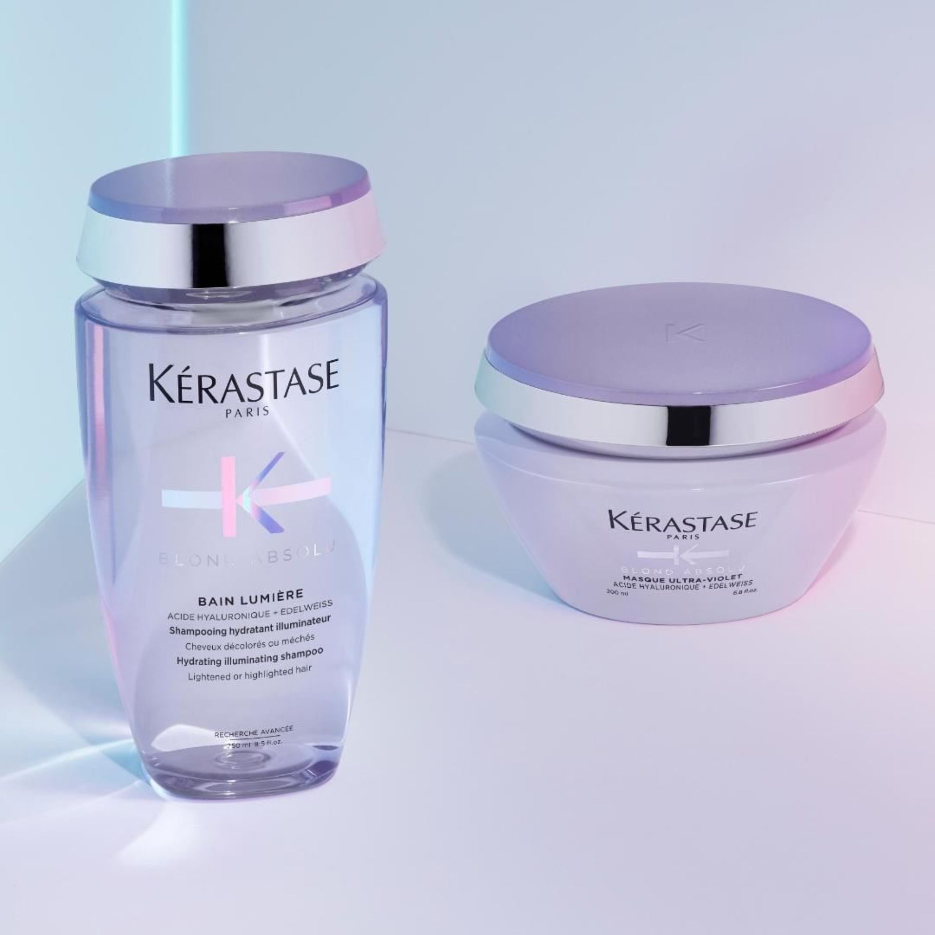 A bottle of Kérastase shampoo and a bottle of Kérastase mask are sitting next to each other on a table