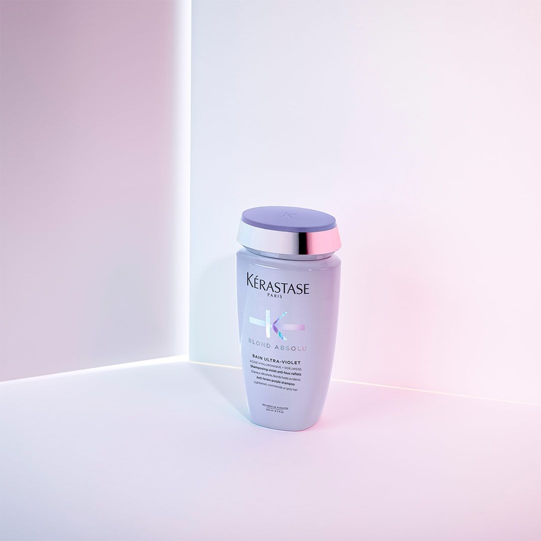 A bottle of shampoo is sitting on a table next to a wall