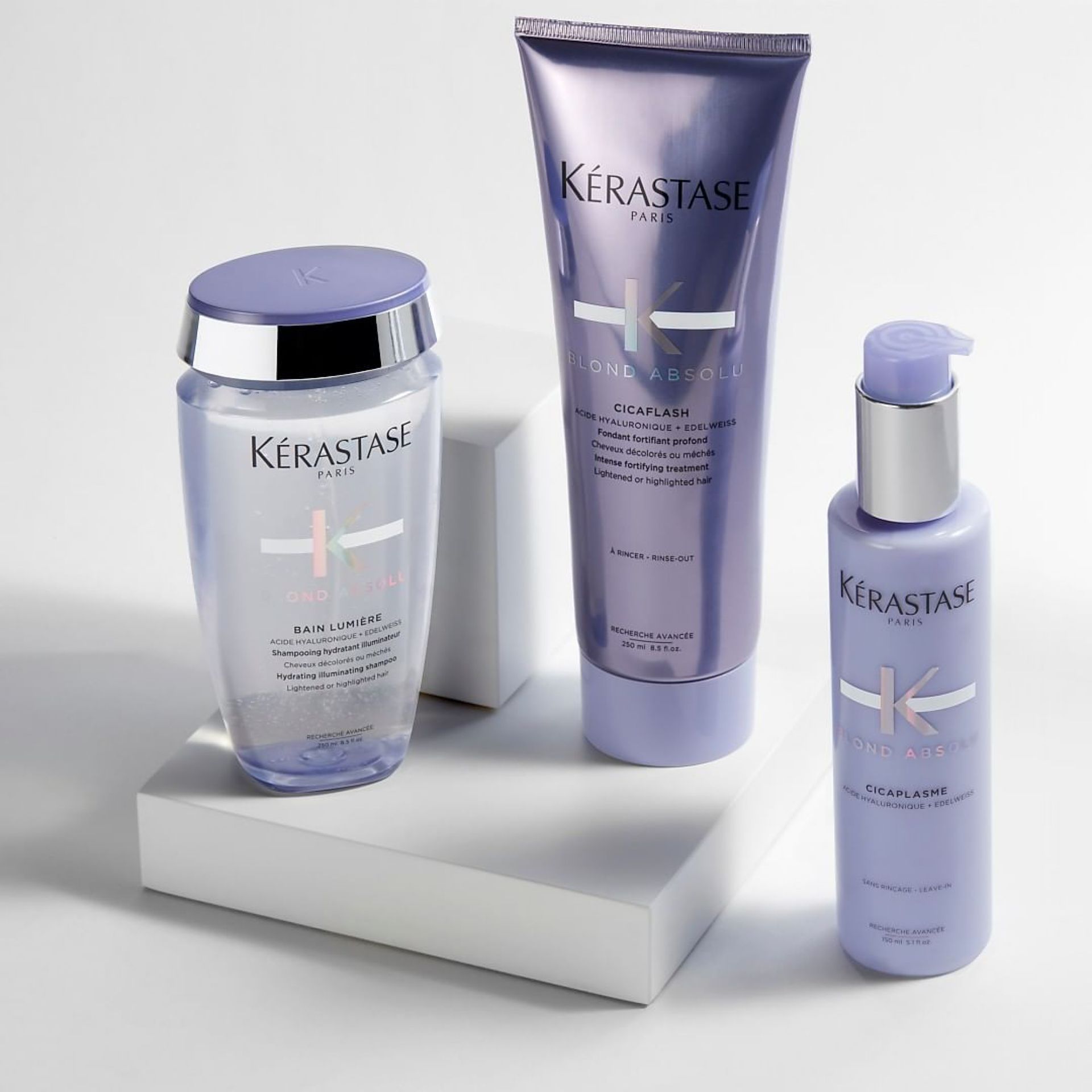 Three bottles of Kérastase hair products are sitting on a white box