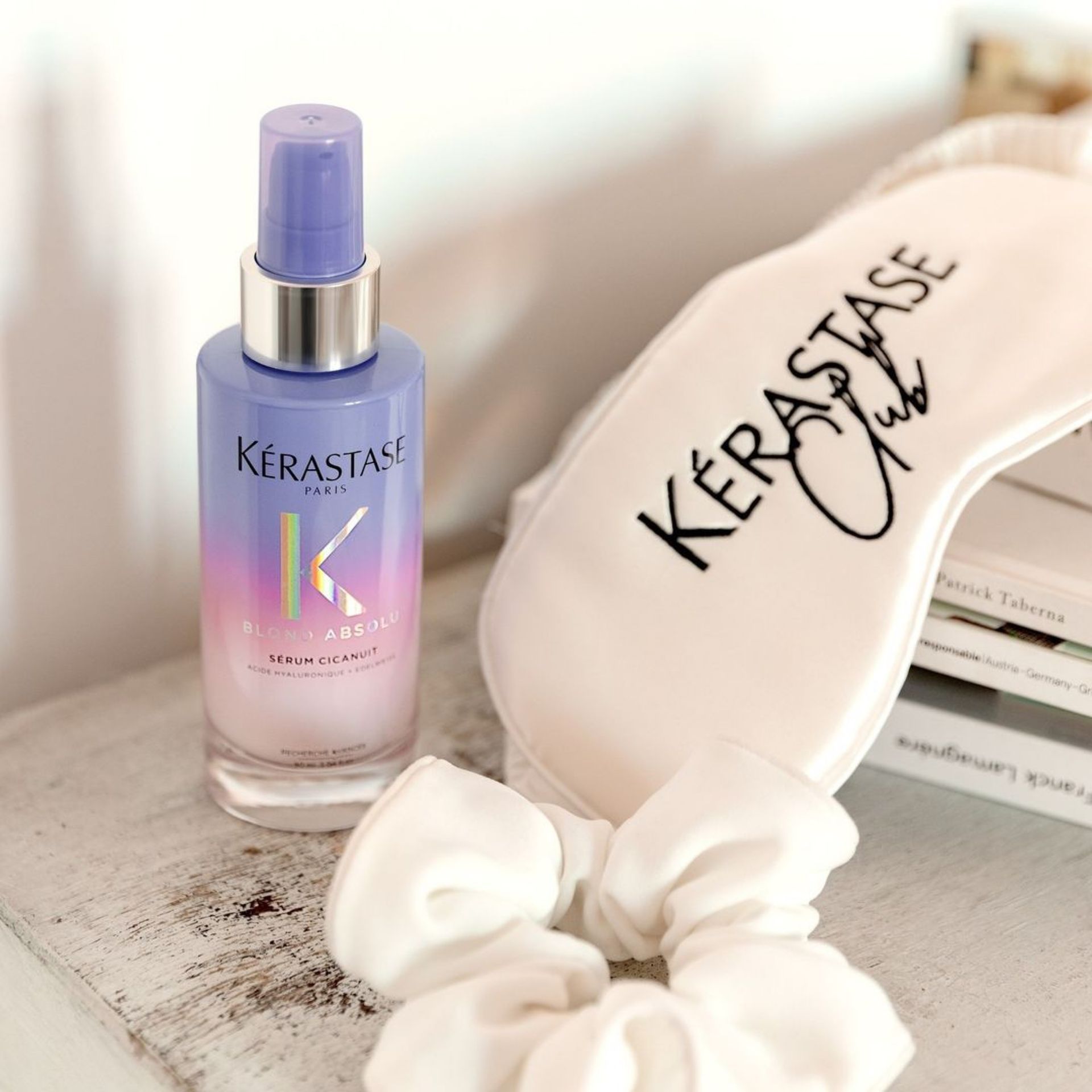 A bottle of Kérastase hair spray next to a Kérastase sleep mask