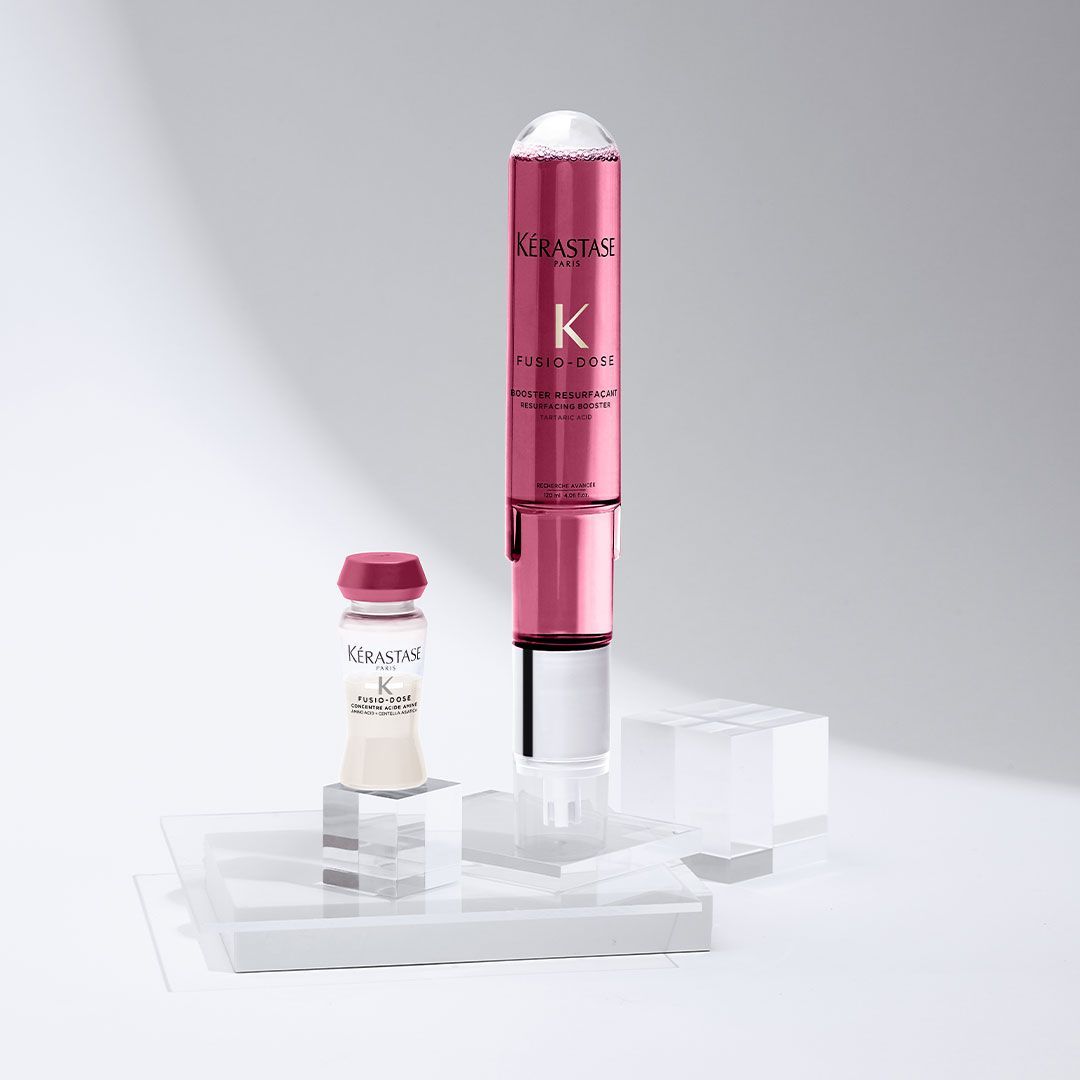 A bottle of shampoo and a bottle of serum are sitting on a table