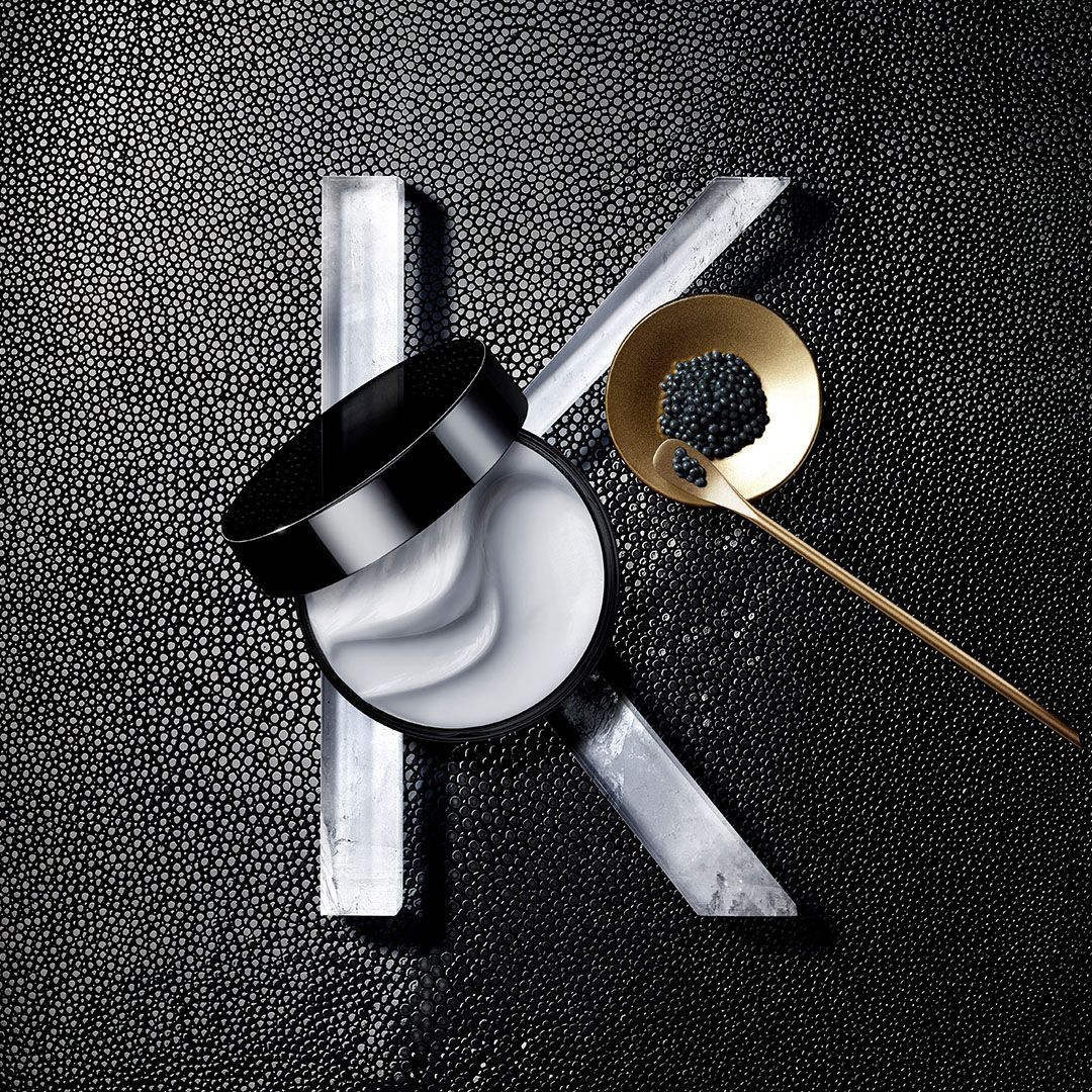 A magnifying glass is sitting on a black surface next to a spoon