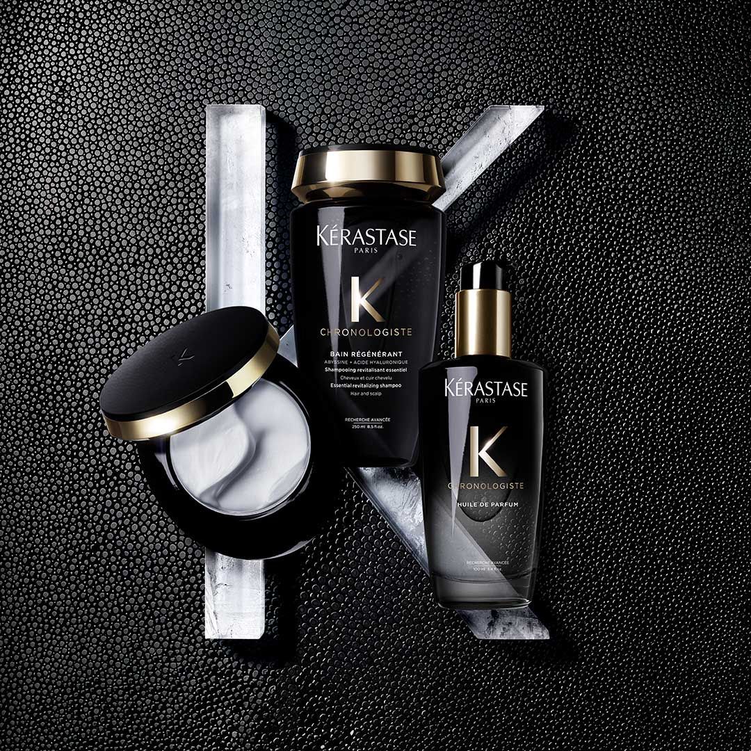 A bottle of shampoo and a bottle of serum are sitting on a black surface