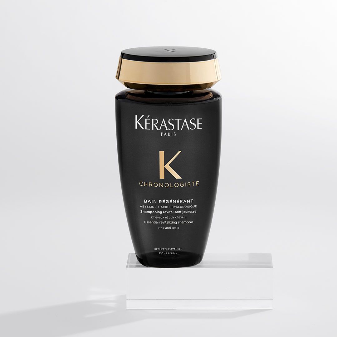 A bottle of Kérastase shampoo is sitting on a white surface