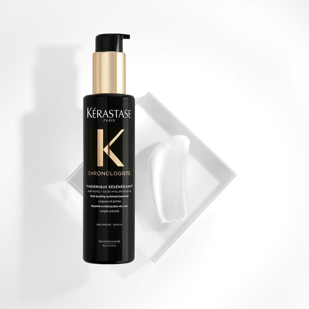 A bottle of Kérastase hair product is sitting on a white surface.