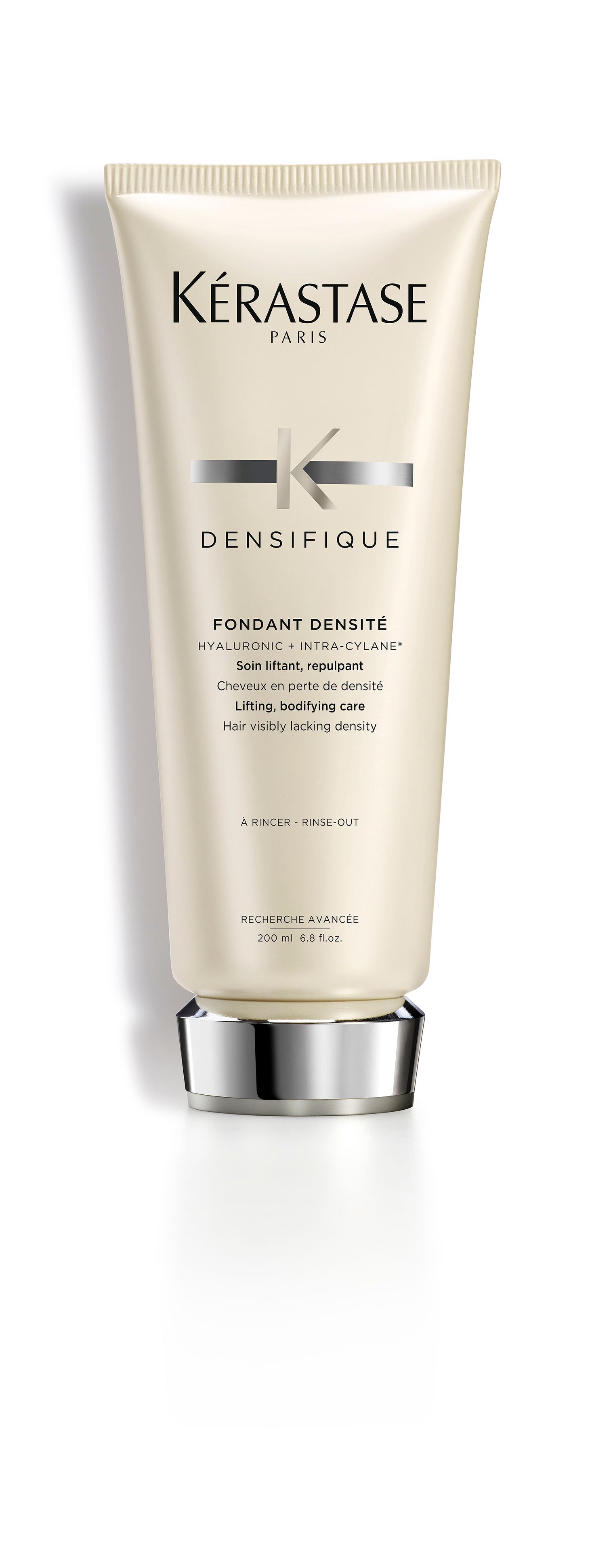 A bottle of Kérastase hair product is sitting on a white surface.