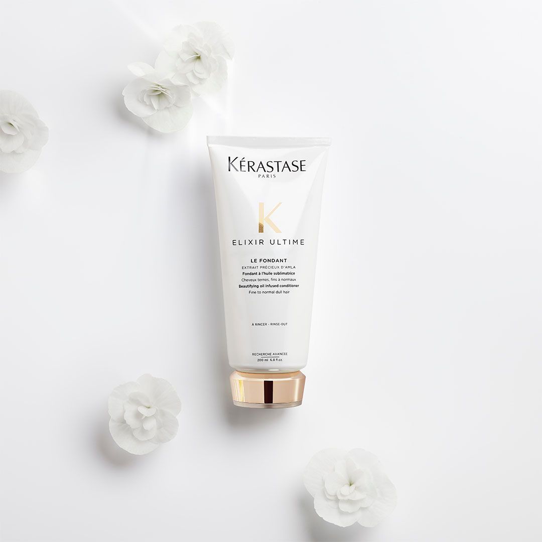 A bottle of Kérastase is surrounded by white flowers