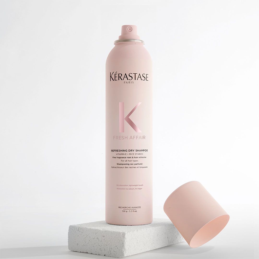 A bottle of Kérastase hair spray is sitting on a white block